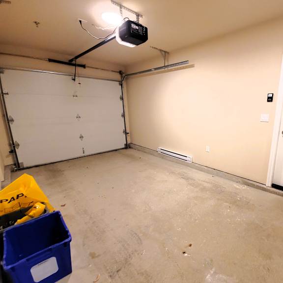 a room with a white door and a white wall with a black speaker hanging from the ceiling.