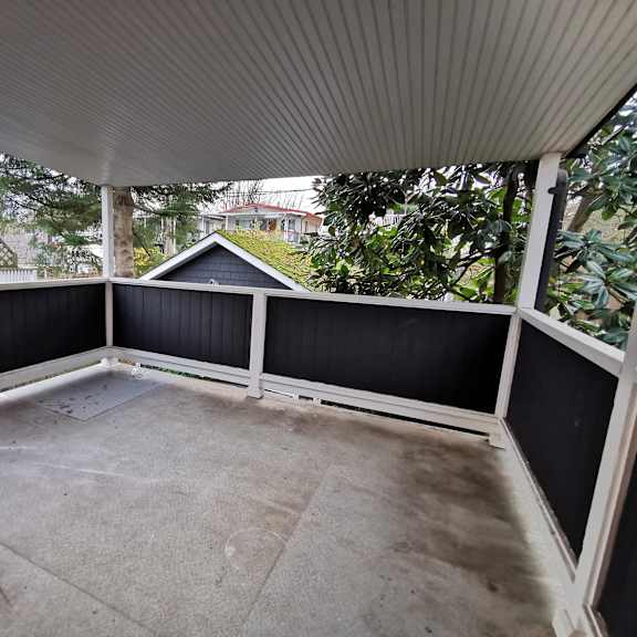 a patio with a white railing and a grey floor.