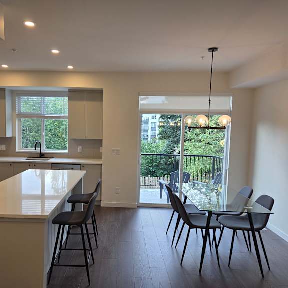 a kitchen with a white counter top and black chairs.
