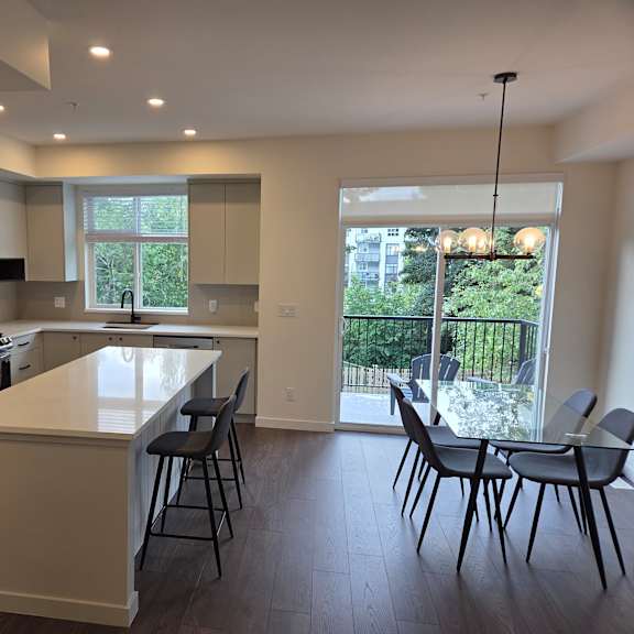 a kitchen with a white counter top and black chairs.