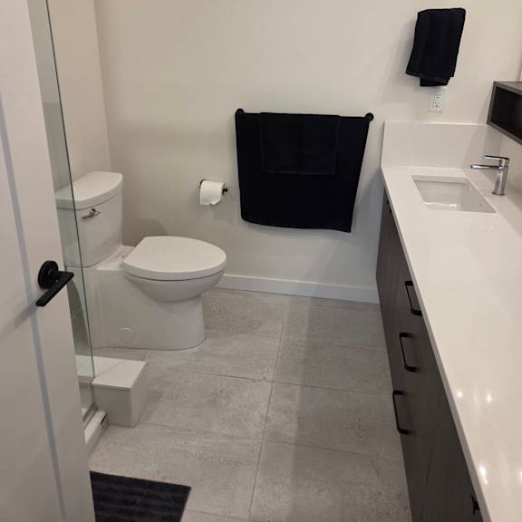a bathroom with a toilet, sink, and a monitor on the wall.