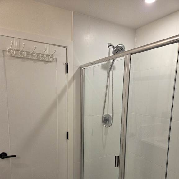 a shower with a glass door and a black handle.