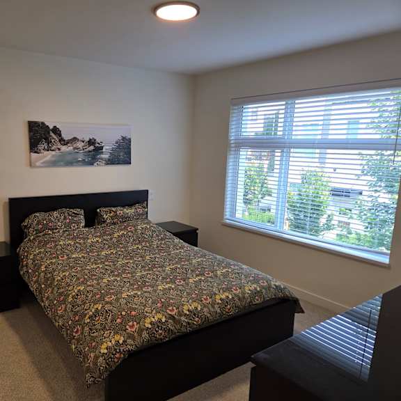 a bedroom with a bed, nightstand, and window.