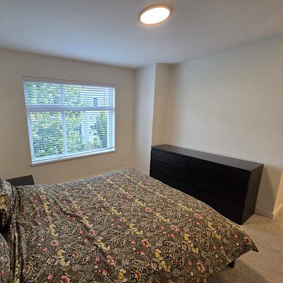 a bedroom with a bed, dresser, and window.