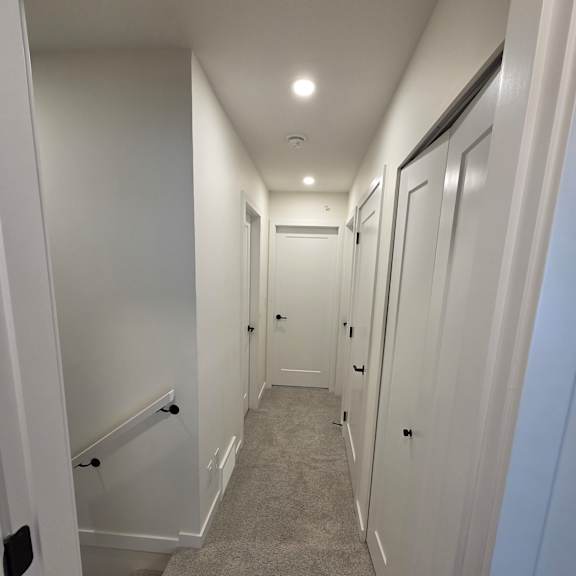a long, narrow hallway with white walls and a concrete floor.