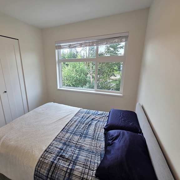 a bedroom with a bed, window, and a door.