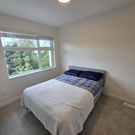 a bedroom with a bed, window, and carpeted floor.