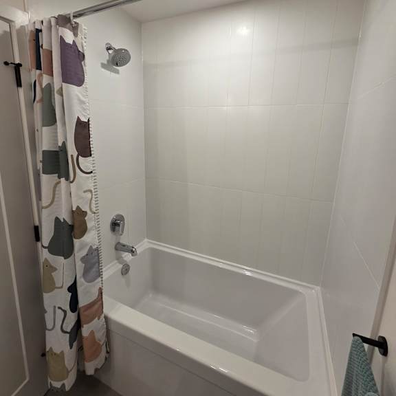 a white bathroom with a shower curtain and a shower head.