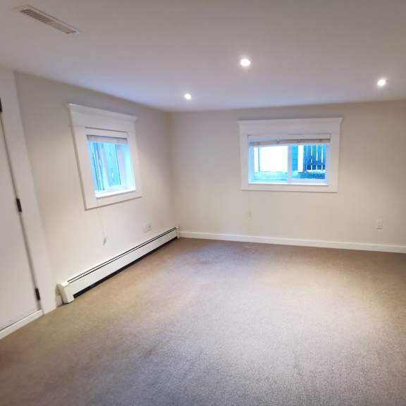 a room with a carpeted floor and two windows.
