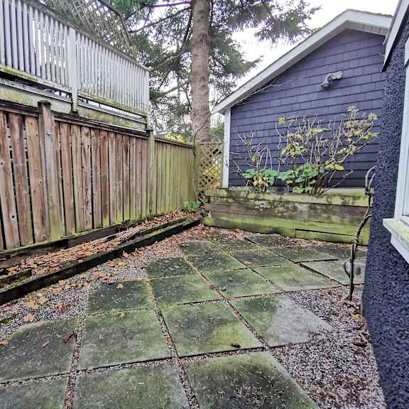 a backyard with a wooden fence and a green tiled patio.