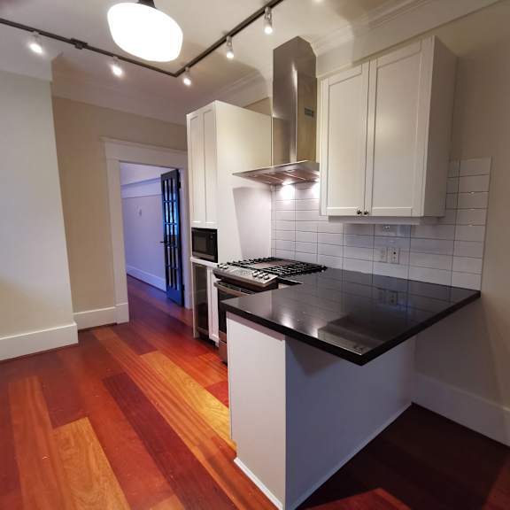 a kitchen with a black counter top and wooden floors.