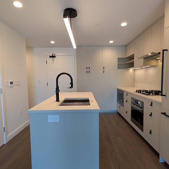 a modern kitchen with a white island and stainless steel appliances.