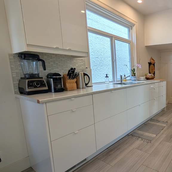 a kitchen with white cabinets and a brick wall.