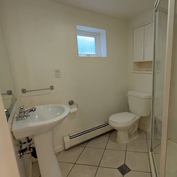 a small bathroom with a toilet, sink, and shower.
