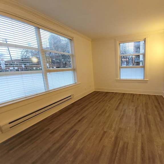 a room with wooden flooring and a window with blinds.