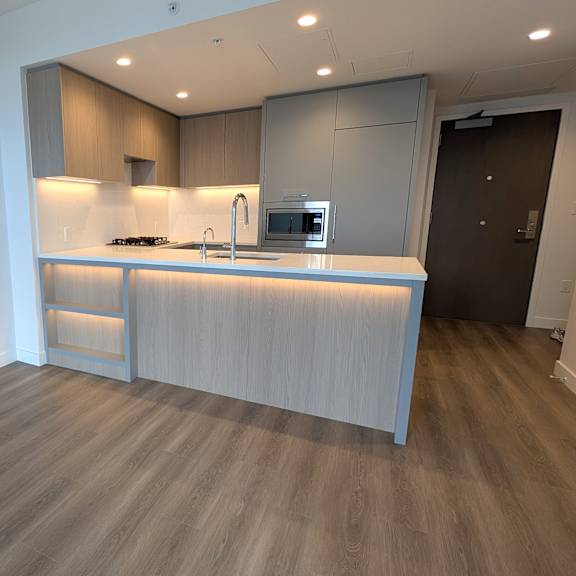 a modern kitchen with a wooden floor and white walls.