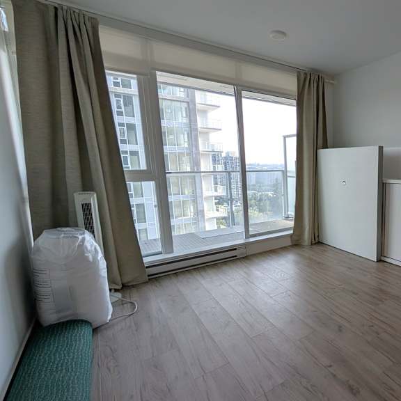 a white refrigerator sits in a room with a window and a chair.