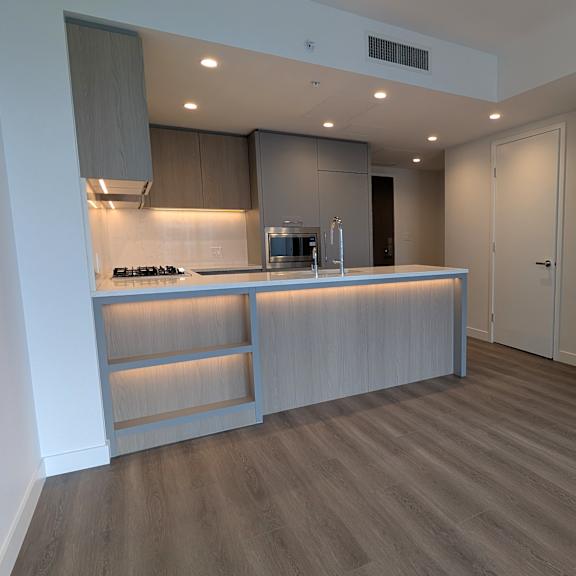 a modern kitchen with a wooden floor and white walls.