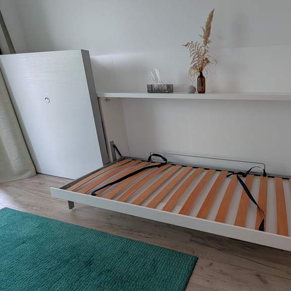a white refrigerator with a shelf and a striped bench in front of it.