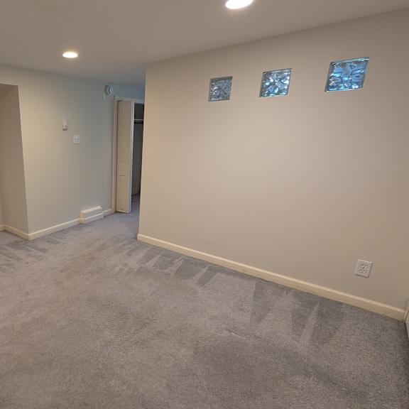 a spacious room with a microwave on top of a counter and a carpeted floor.