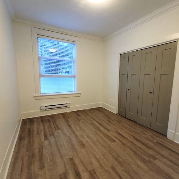 a room with a brown floor and a grey wardrobe.
