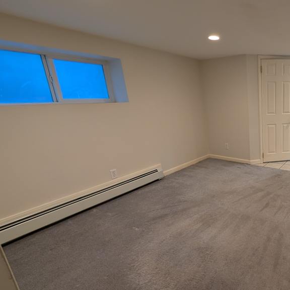 a spacious empty room with a kitchenette in the corner.
