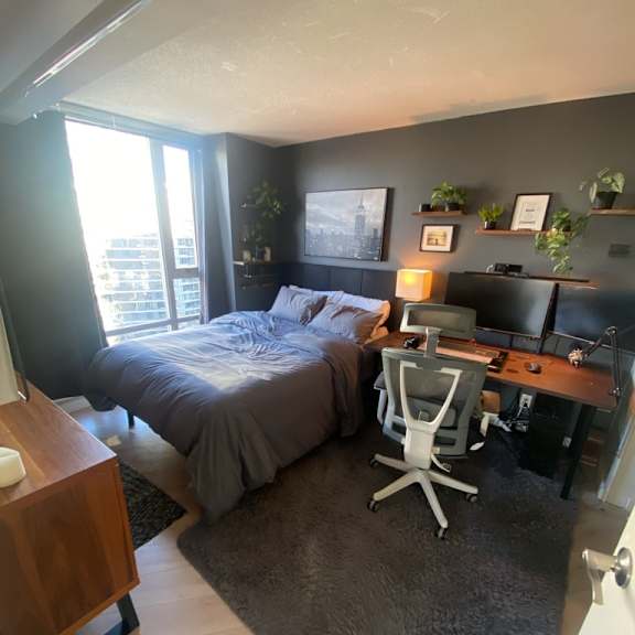 a bedroom with a bed, desk, and chair.