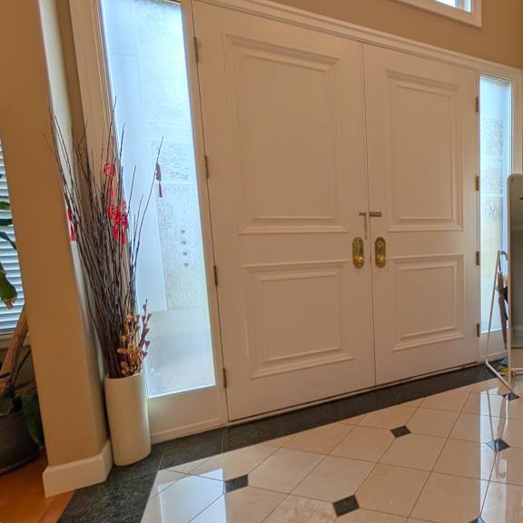 a white door with a gold handle is in a room with a brown chair.