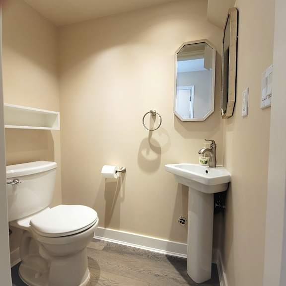 a bathroom with a toilet, sink, and mirror.
