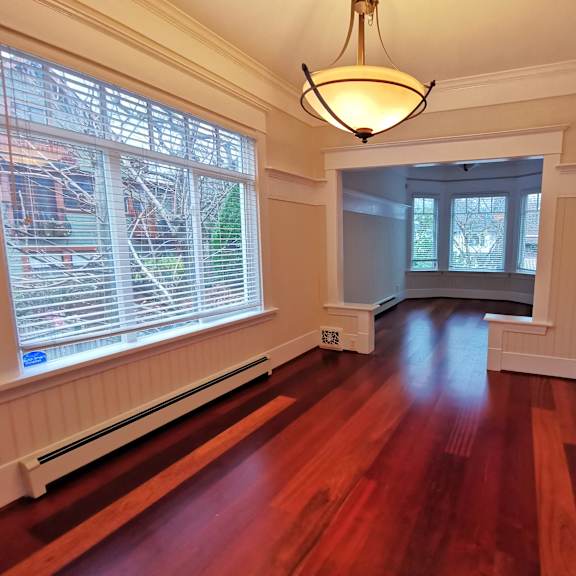 a room with wooden floors and a window with blinds.