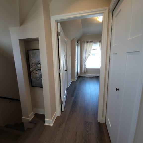 a hallway with a white door and a painting on the wall.