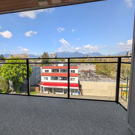 a balcony with a view of a red building and mountains.