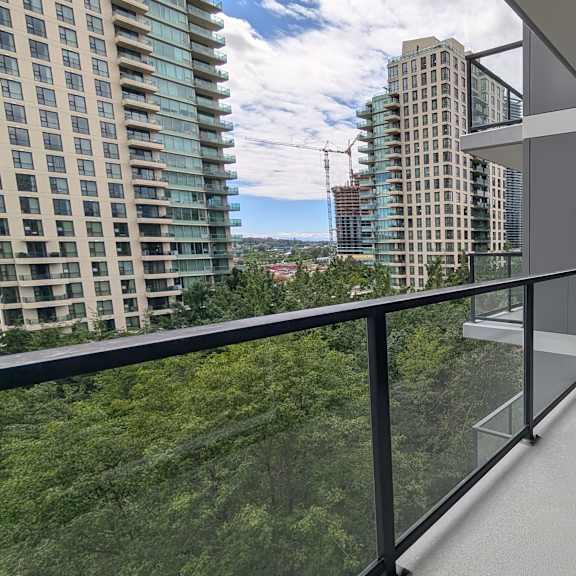 a balcony with a glass railing overlooks a cityscape.