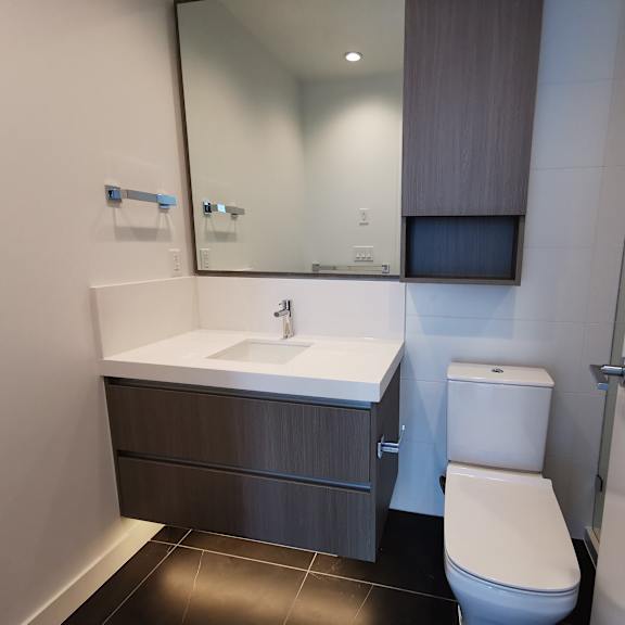 a white toilet sits next to a sink in a modern bathroom.