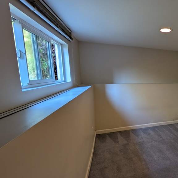 a room with a window and two pictures on the wall.