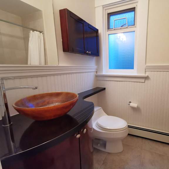 a bathroom with a toilet, sink, and a window.