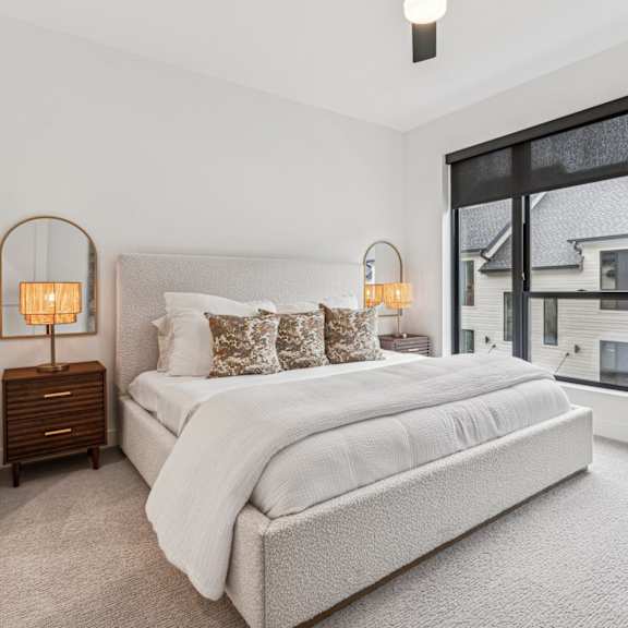 Thumbnail 9 of 11 A bedroom with a large bed and two lamps on side tables.