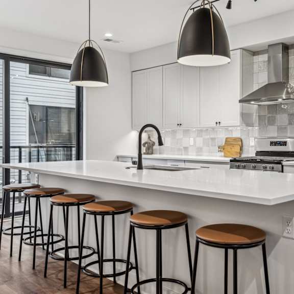 Thumbnail 7 of 11 A modern kitchen with white countertops and stainless steel appliances.