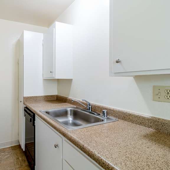 a kitchen with a stove, sink, and cabinets.