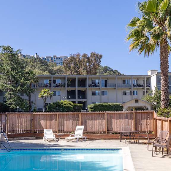 a pool surrounded by a wooden fence and chairs.
