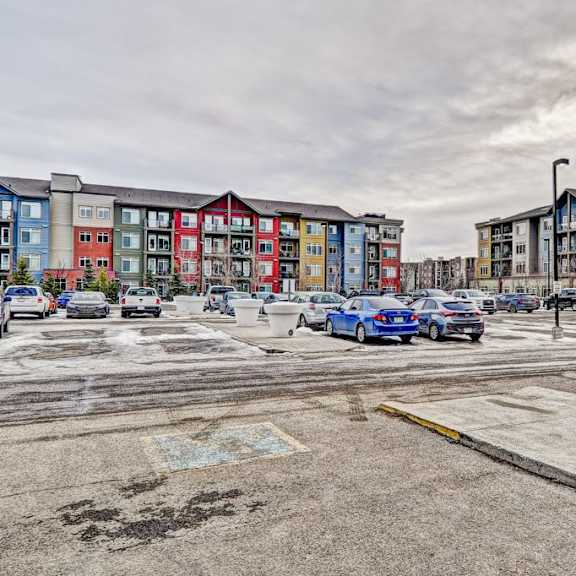 a parking lot with cars and apartment buildings in the background.