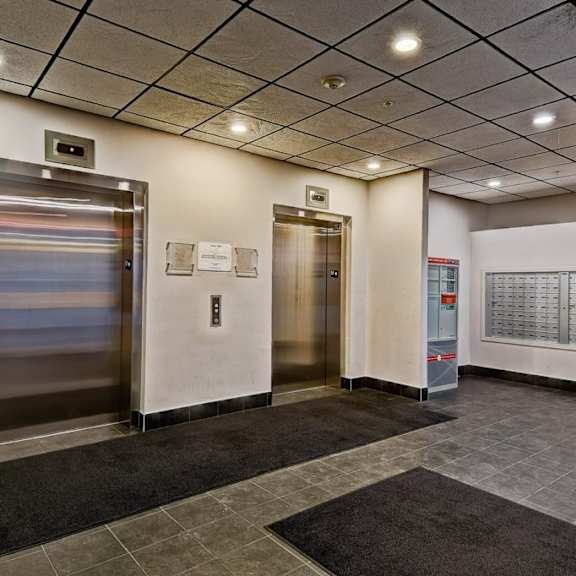 a hallway with two elevators and a calendar on the wall.
