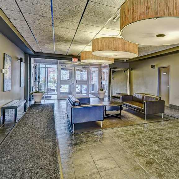 a spacious waiting area with a bench, a table, and a painting on the wall.