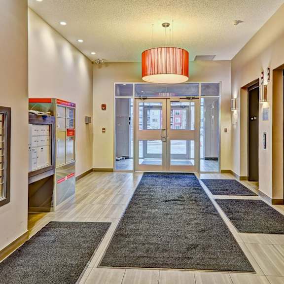 a hallway with a red chandelier and a black door.