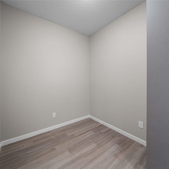 an empty room with wood flooring and white walls
