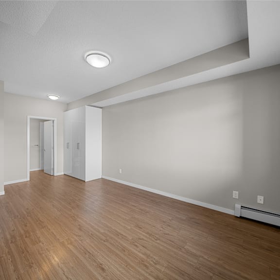 the living room is empty and has a wood floor and white walls