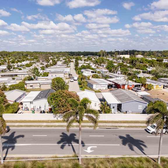 a street view of a residential area with houses and palm trees.