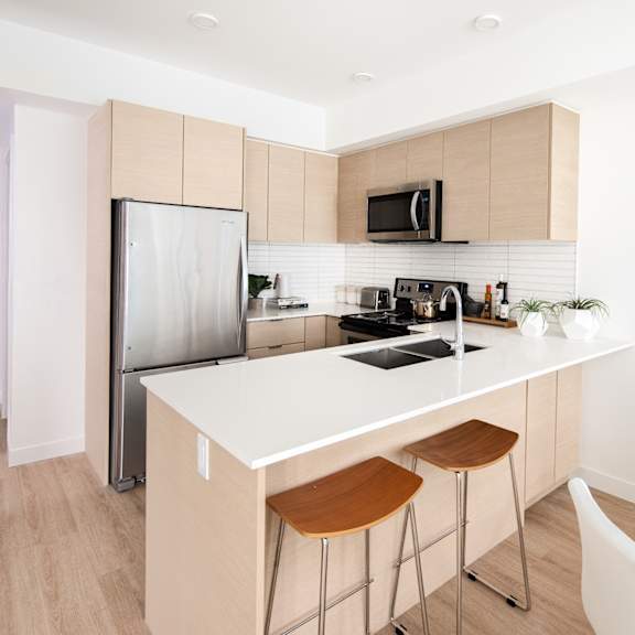 a modern kitchen with a white countertop and wooden cabinets.