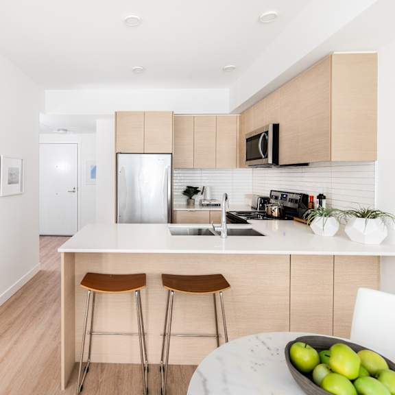 a kitchen with a white counter top and a bowl of green apples on it.