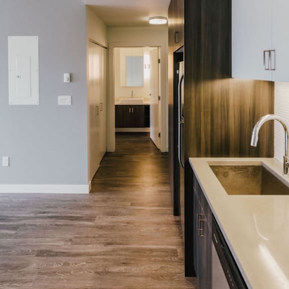 a modern kitchen with a sink and a long hallway.